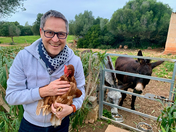Martin mit Huhn auf dem Arm und zwei Eseln im Hintergund
